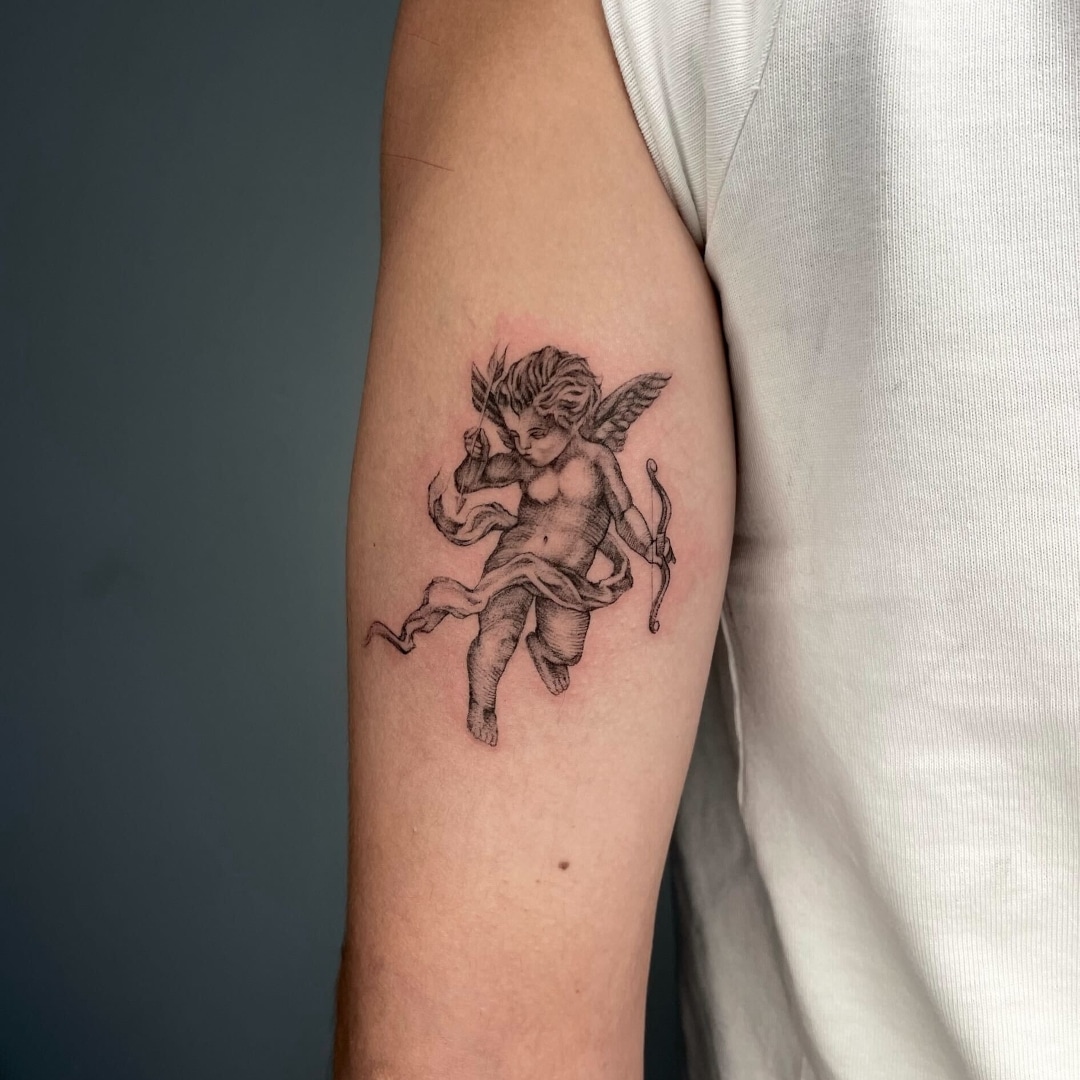 Tattoo of a cherubic figure with wings and bow