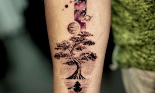 Stunning tattoo of a tree, planets, and galaxy on arm.