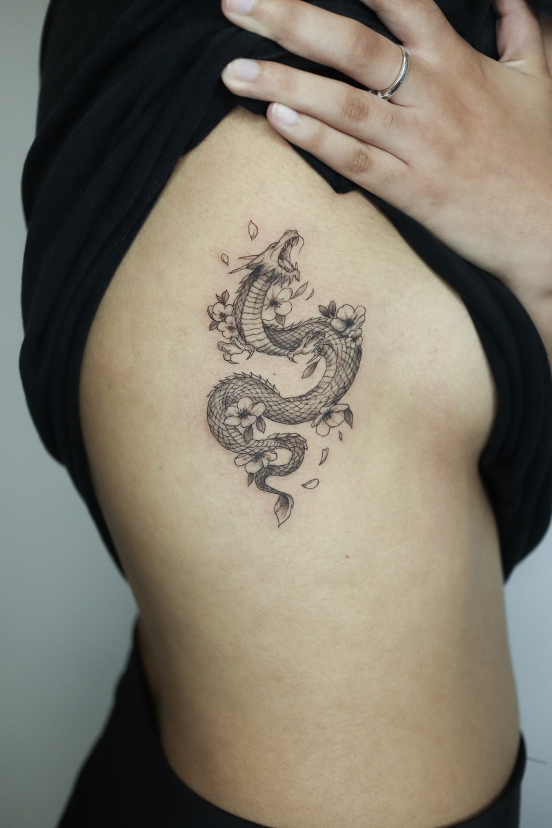 Tattoo of a snake with floral elements on skin