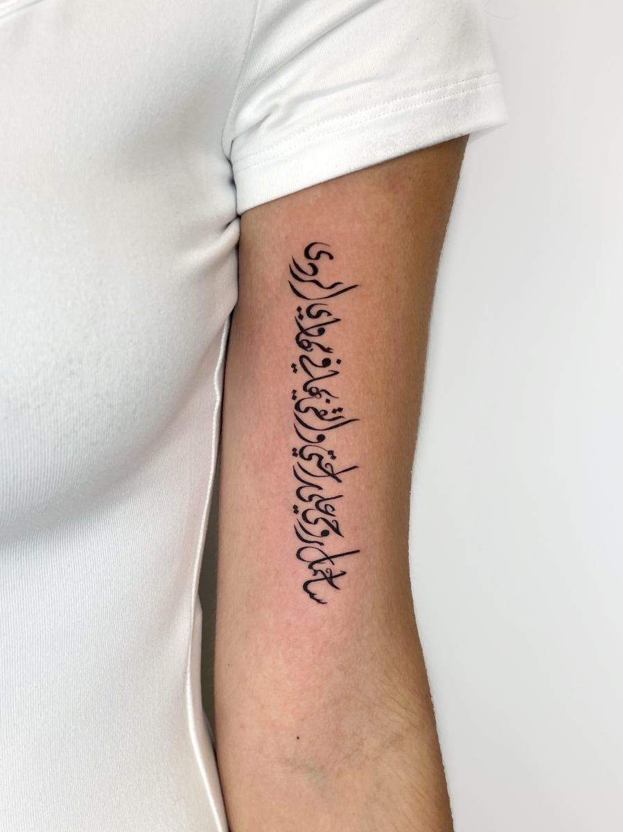 Tattoo on a person's arm featuring intricate script