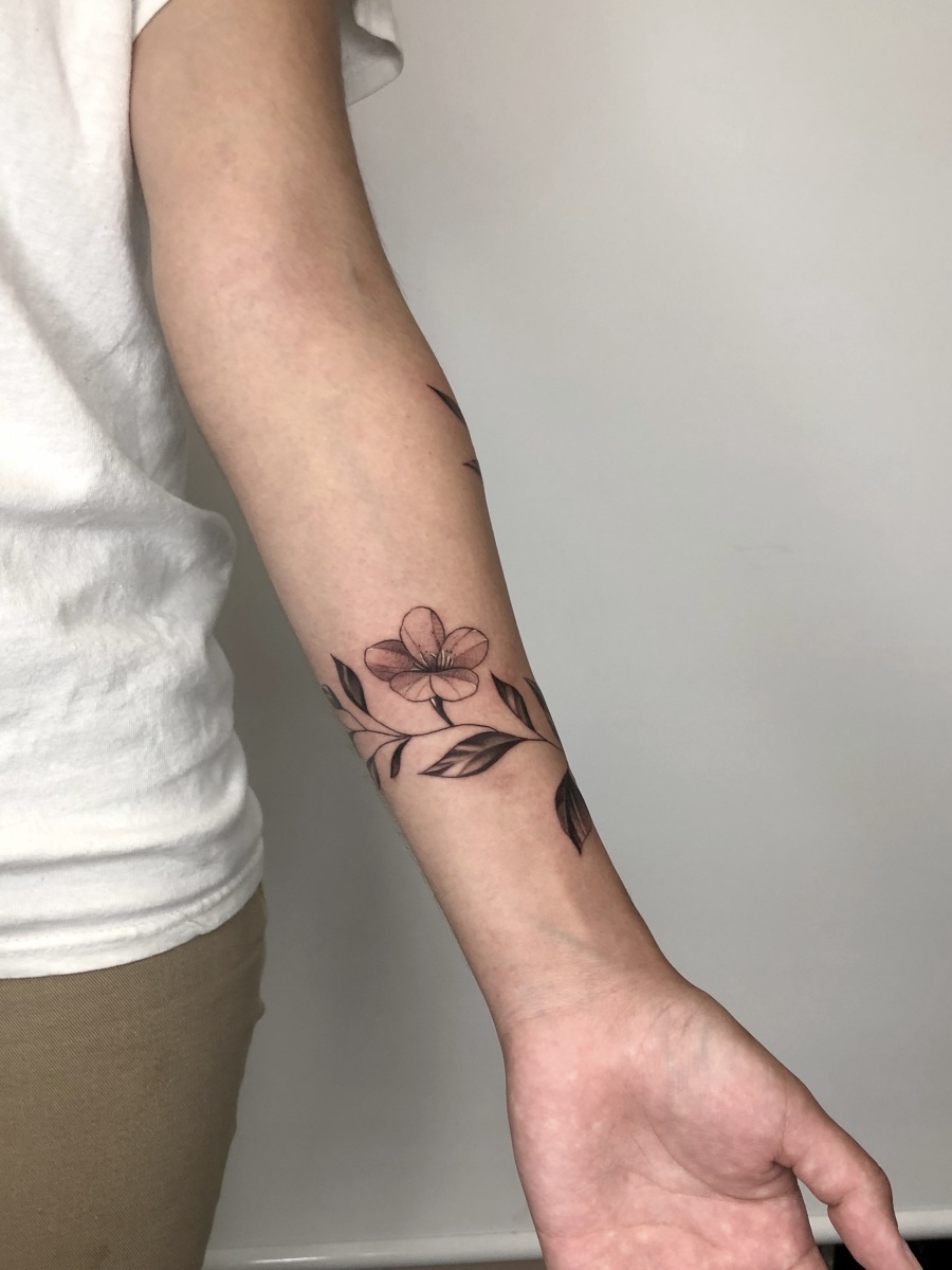 Floral tattoo on arm with delicate leaves