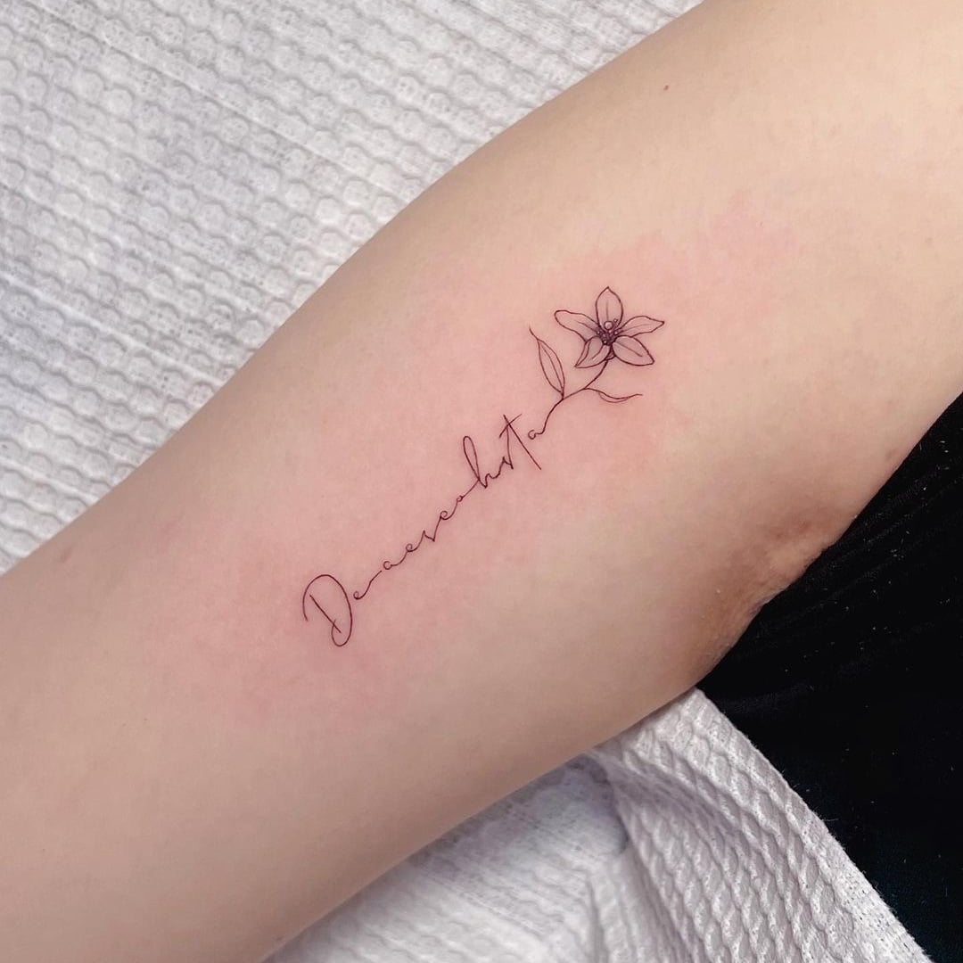 Delicate floral tattoo on arm with elegant lettering