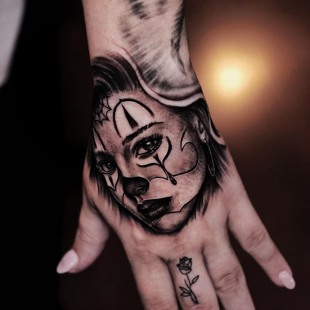 Tattooed hand featuring a woman's face and rose design