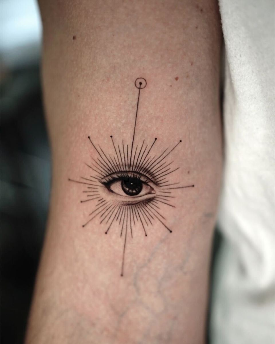 Black ink tattoo of an eye surrounded by rays