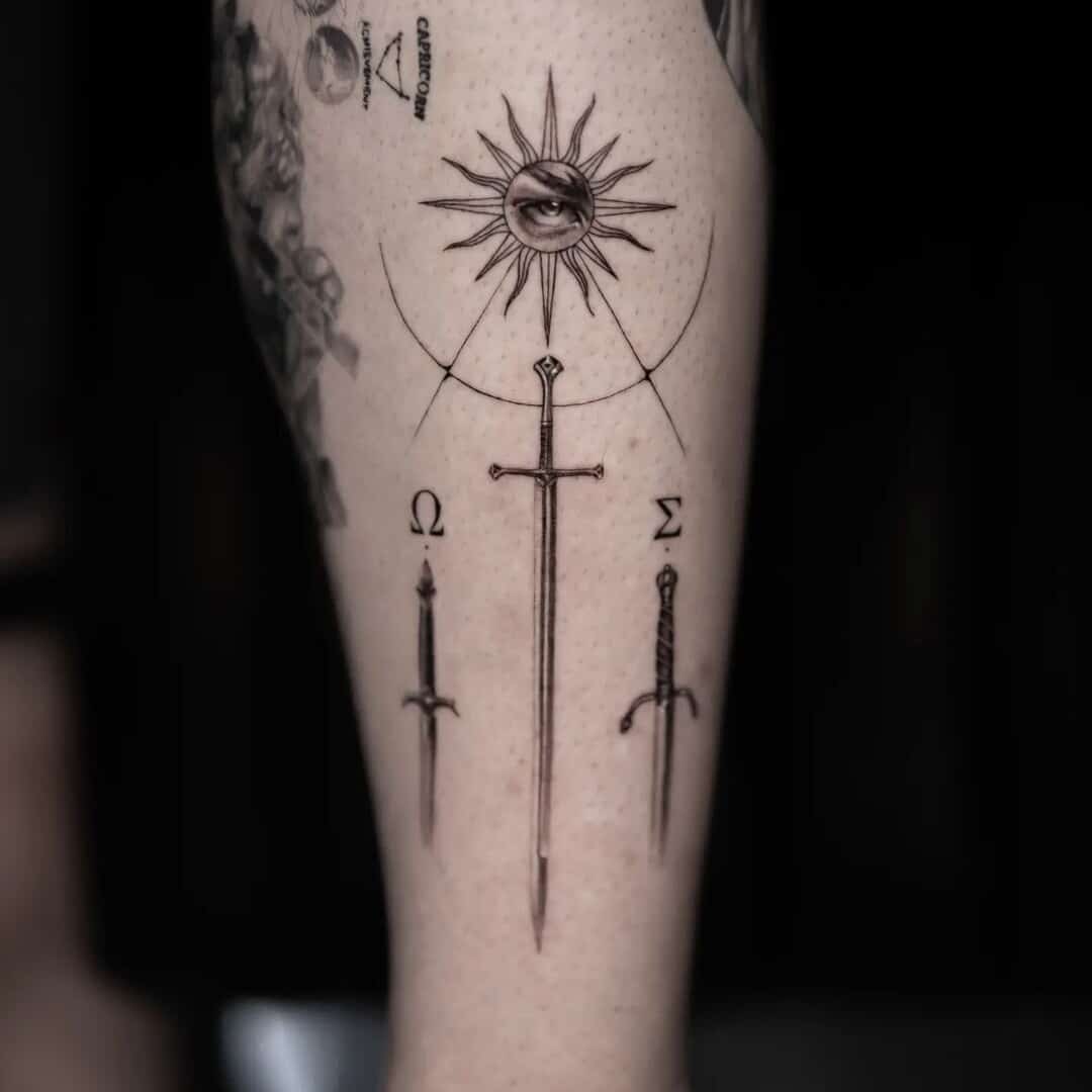 A detailed tattoo featuring a sword, sun, and eye symbol.