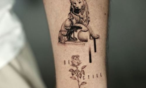 A detailed tattoo depicting a lion with a rose and text.