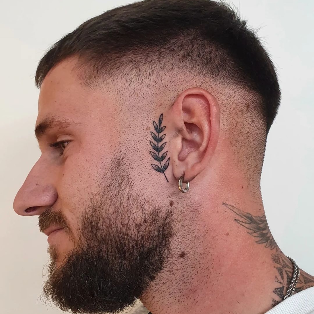 Man with a leaf tattoo on the side of his head