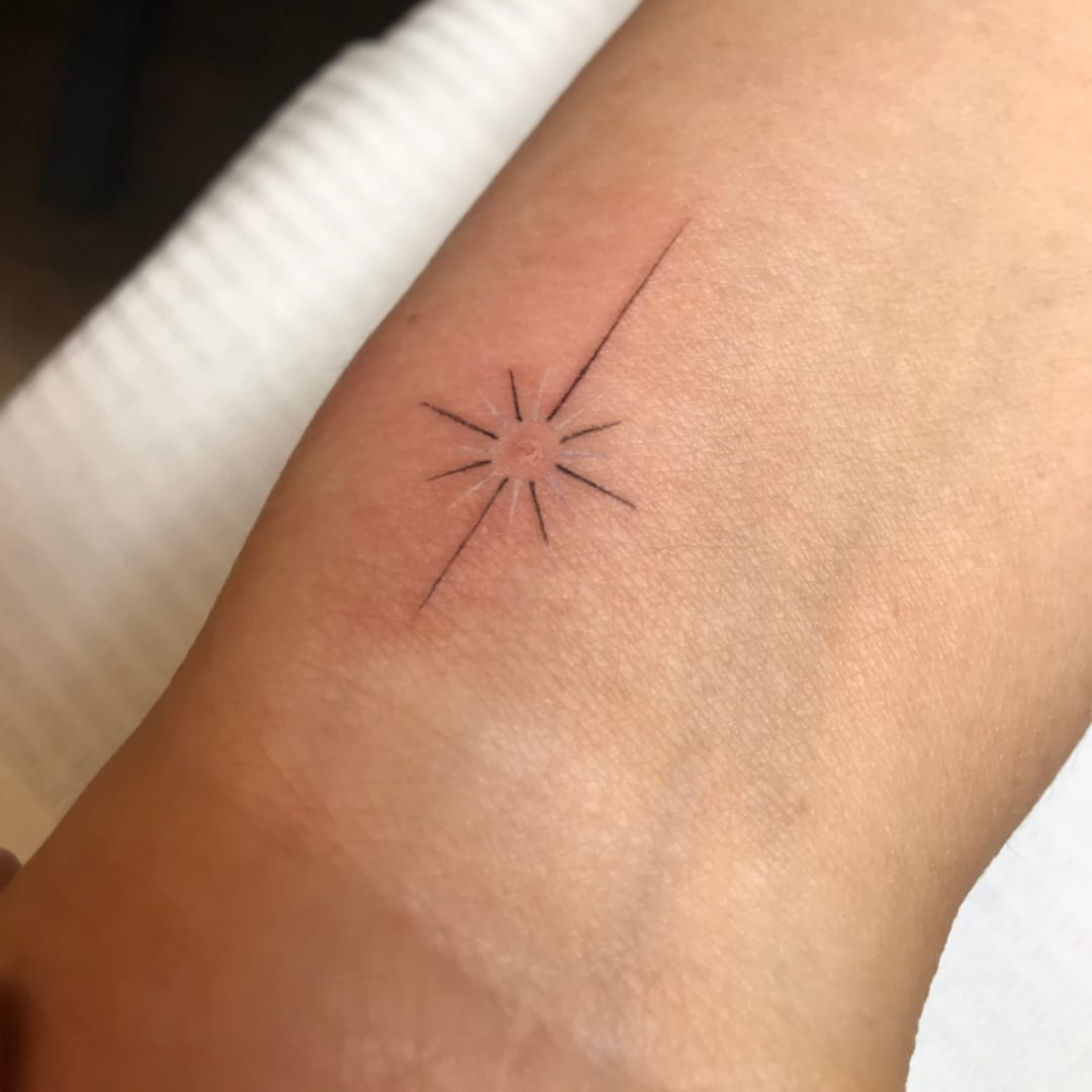 Minimalistic sun tattoo on wrist