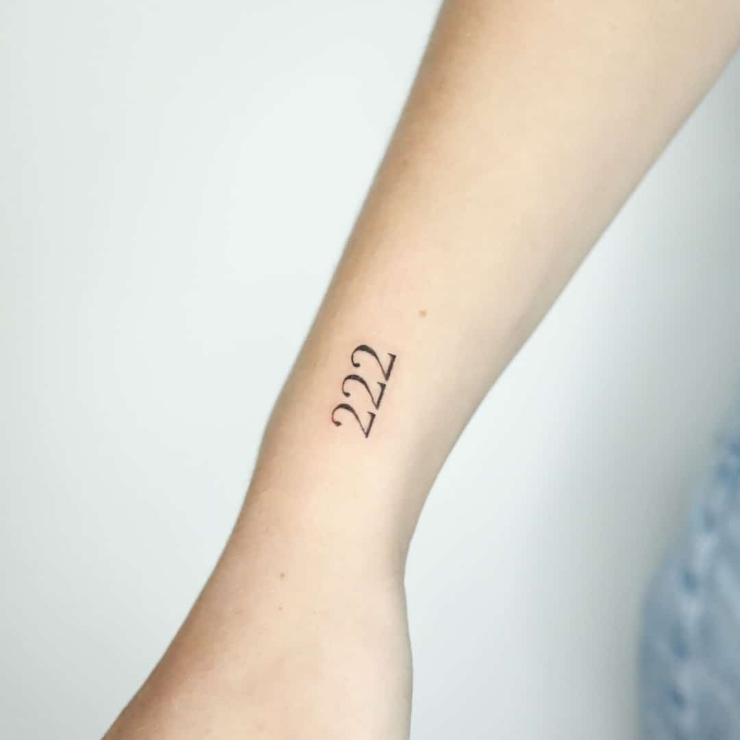 Close-up of a tattoo featuring the numbers 222 on a forearm