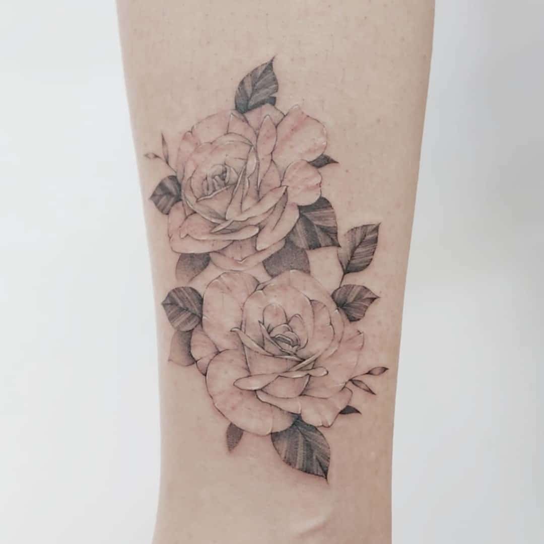 Delicate tattoo of two pink roses on a light skin arm