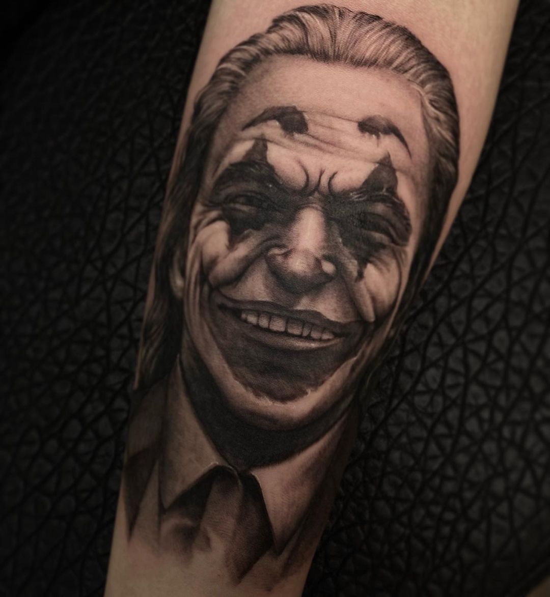 Realistic black and gray tattoo of a smiling clown face on skin