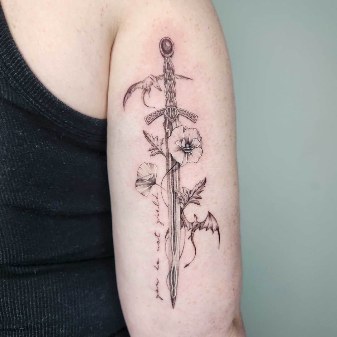 Intricate sword tattoo featuring flowers and bats on arm