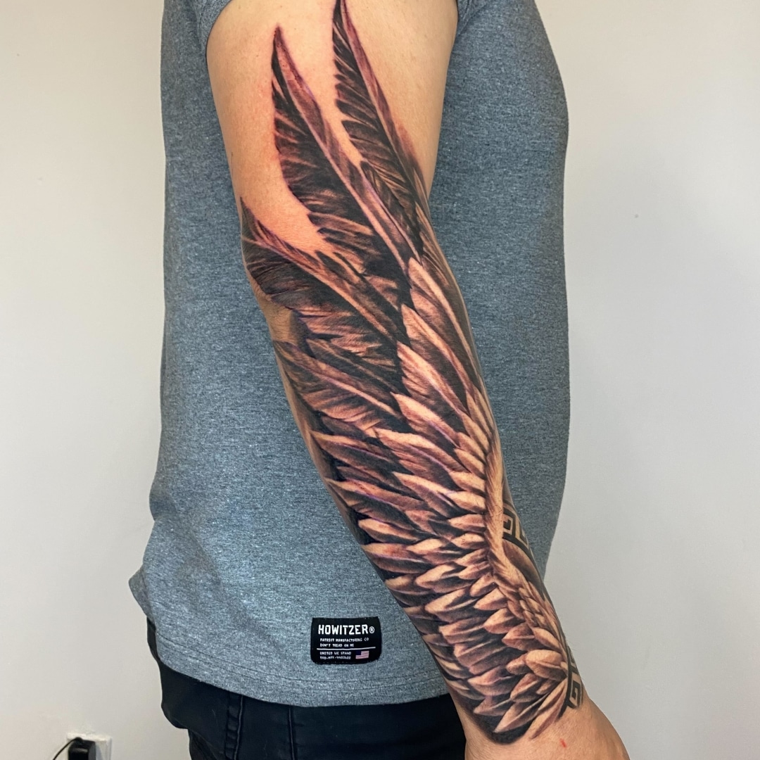 Detailed tattoo of eagle feathers on a man's arm