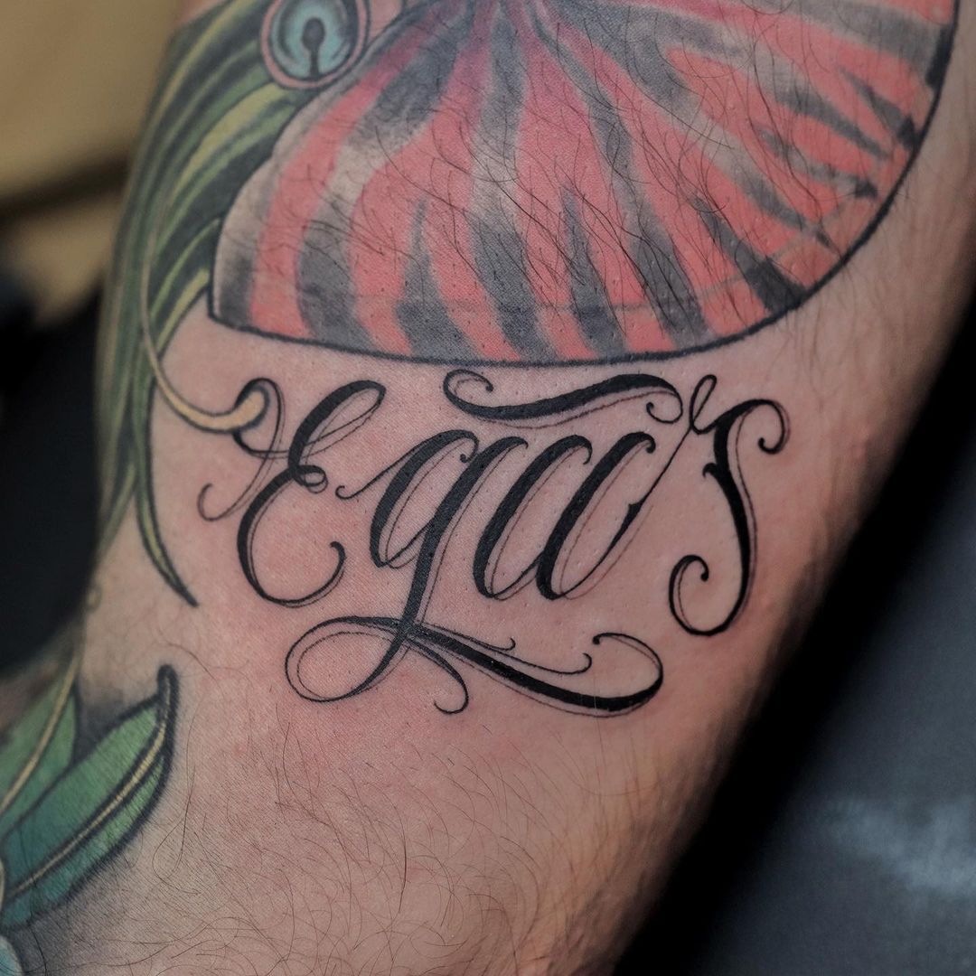 Close-up of a tattoo featuring the word 'Egas' and colorful designs