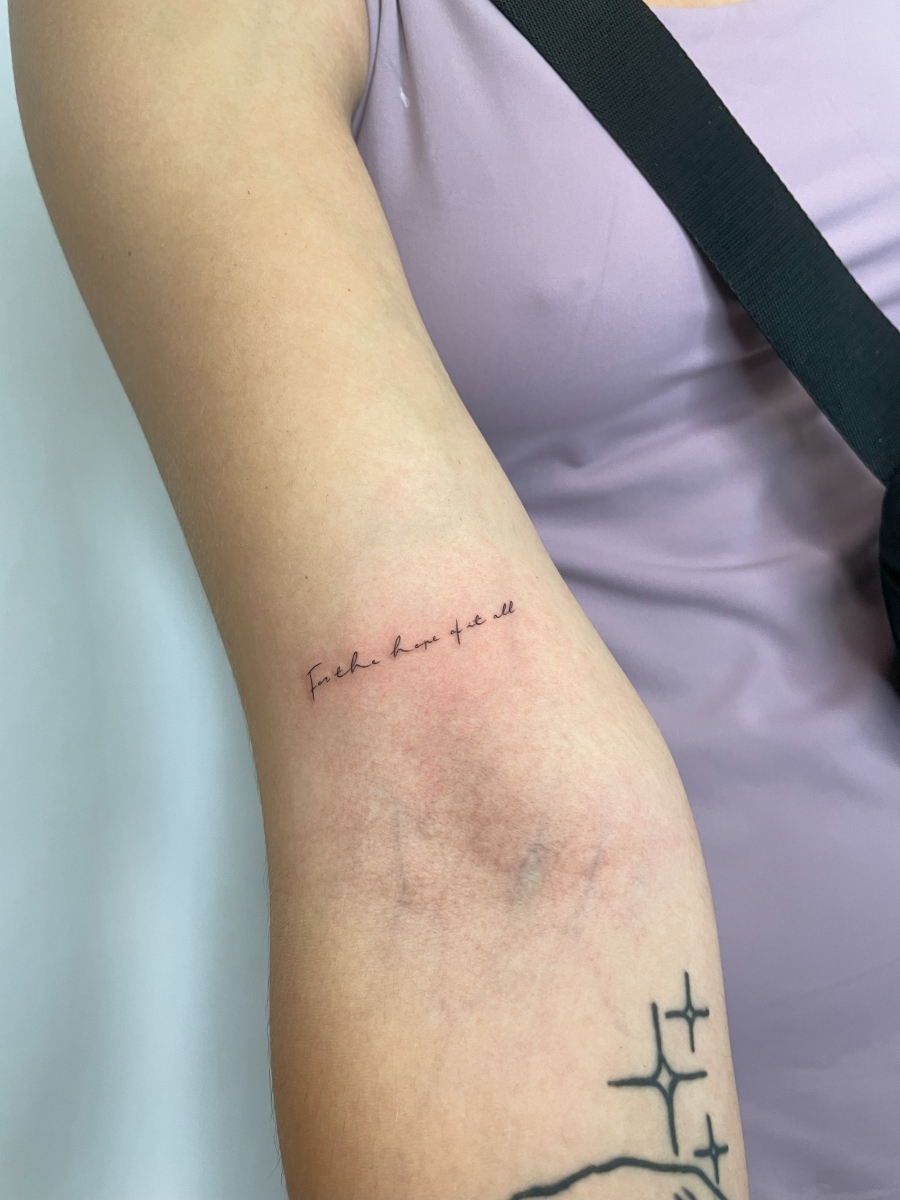 Close-up of a person's arm with a tattoo that reads 'fuck love all'.