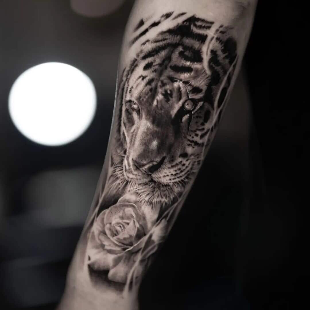 Black and white tattoo of a tiger and rose on arm