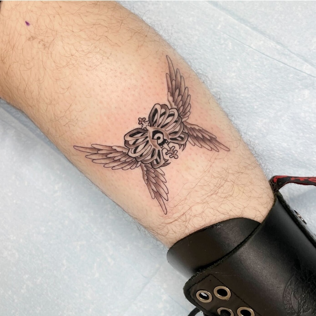 Detailed tattoo design featuring a skull with wings on a leg.