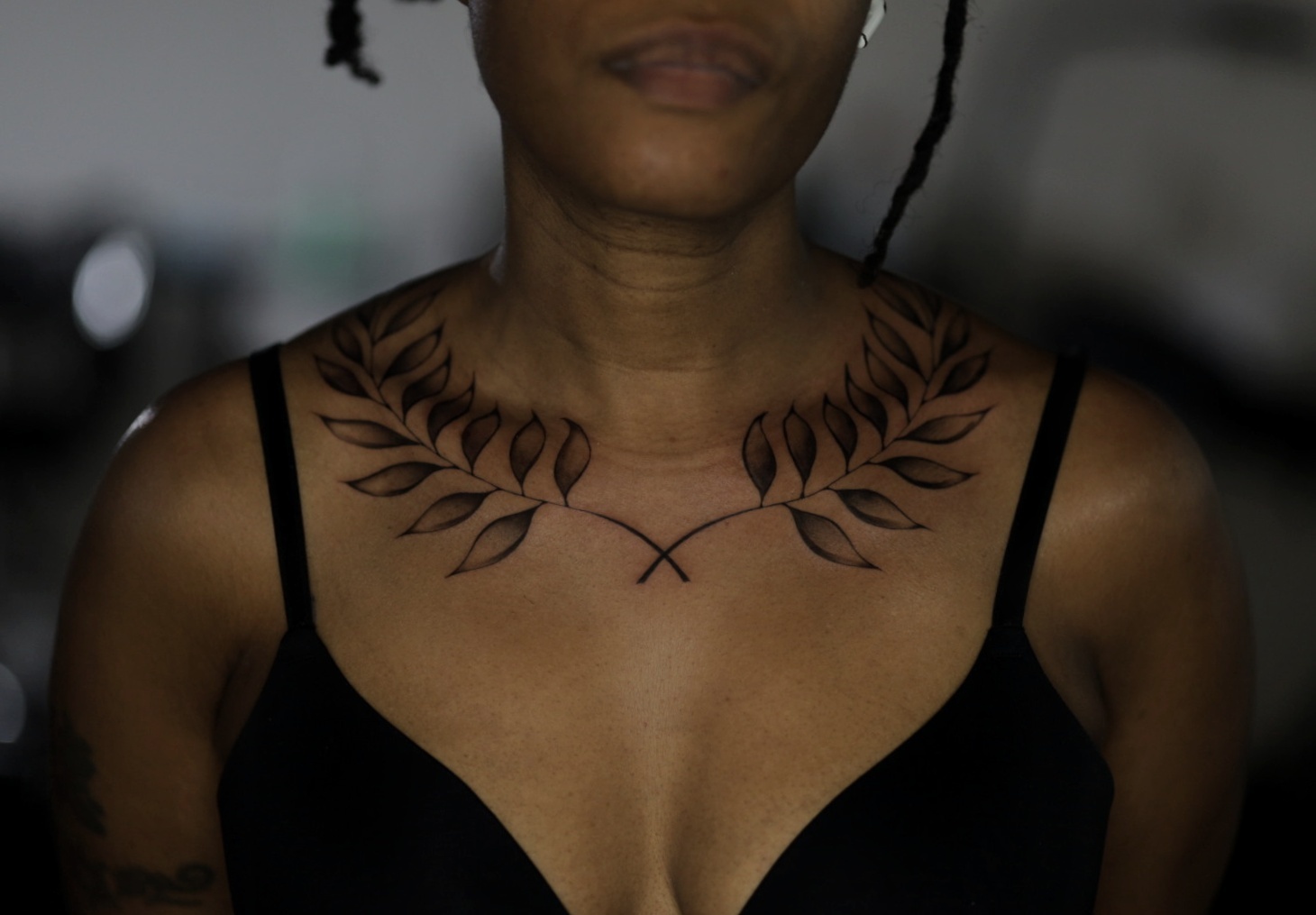 A person with a leaf design tattoo on their collarbone
